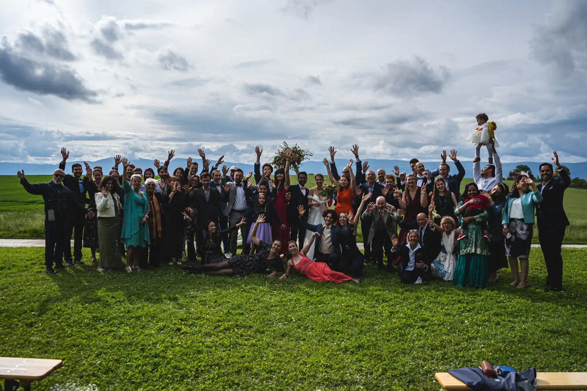 Large group of wedding guests cheering on a lawn