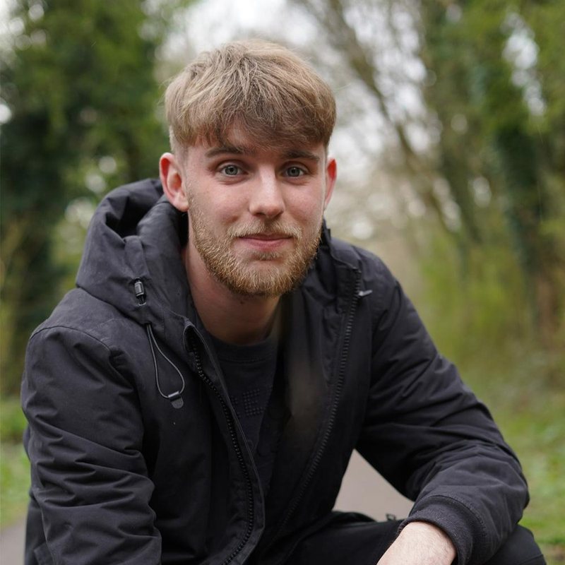 Ben Rose crouching outdoors in a dark jacket