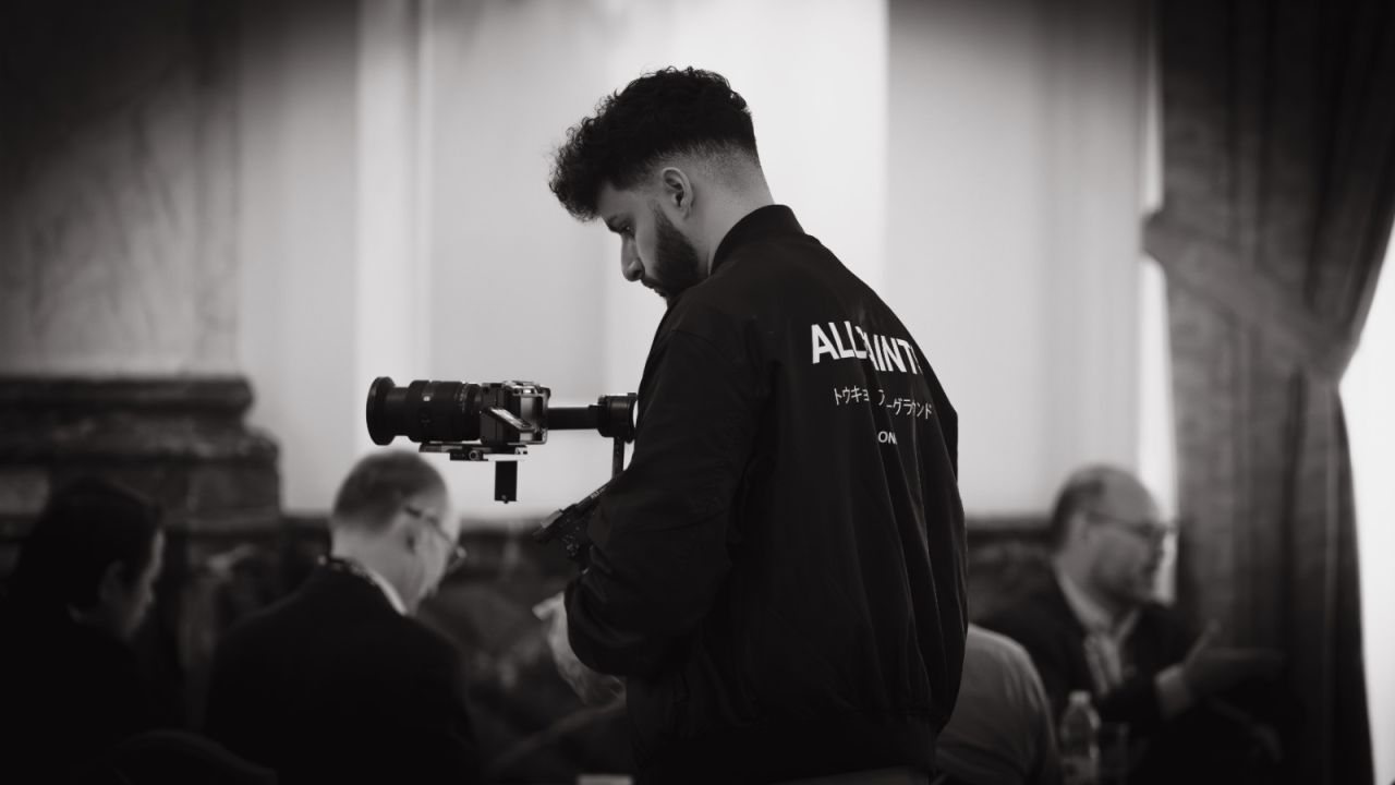 Black and white photo of a camera operator with a gimbal filming guests at a conference